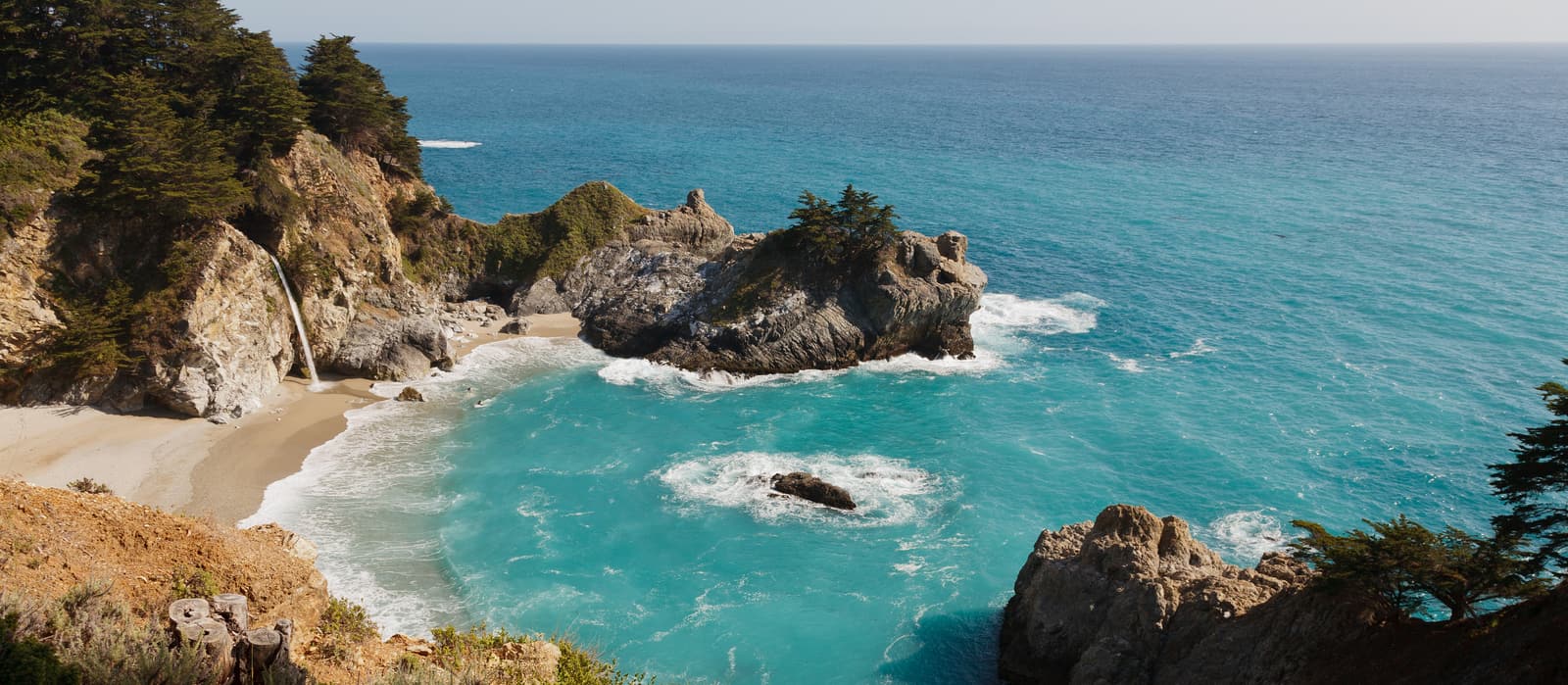 McWay Falls spilling onto the beach at a turquoise cove in Big Sur, California